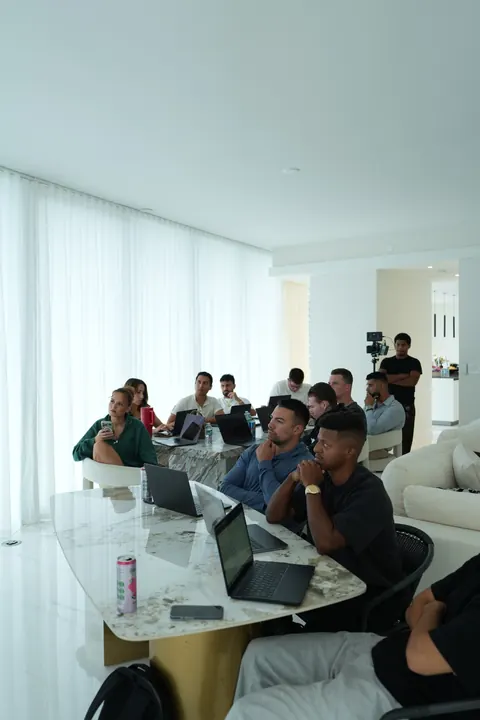 Agency owners around a marble table with laptops open, following the session