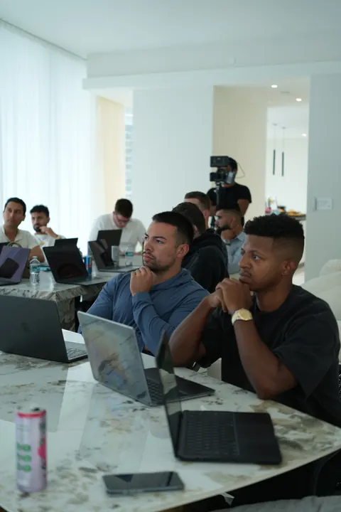 Two attendees listening closely, laptops open in front of them